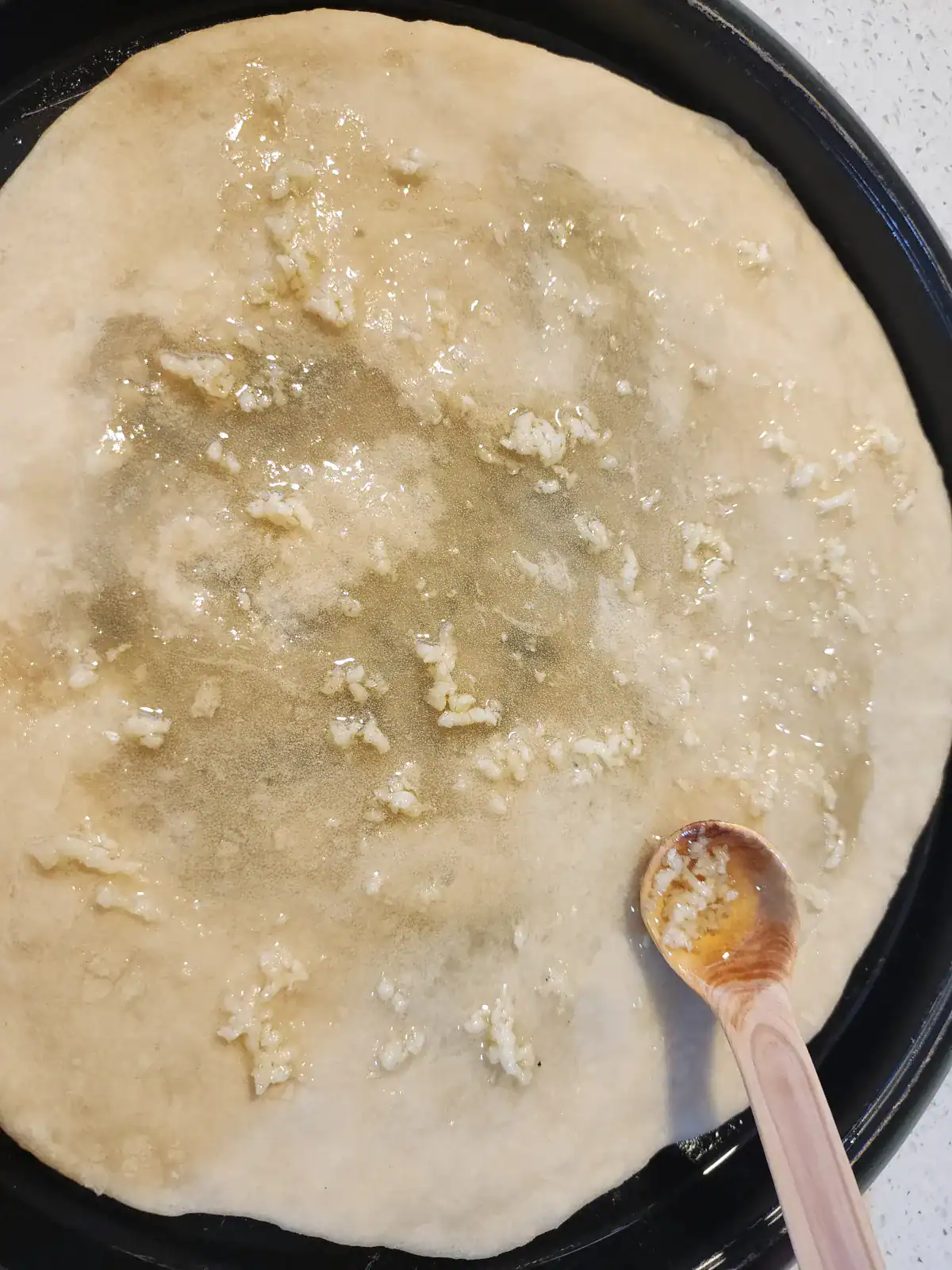 Applying garlic, oil and salt mixture (pizza toppings)