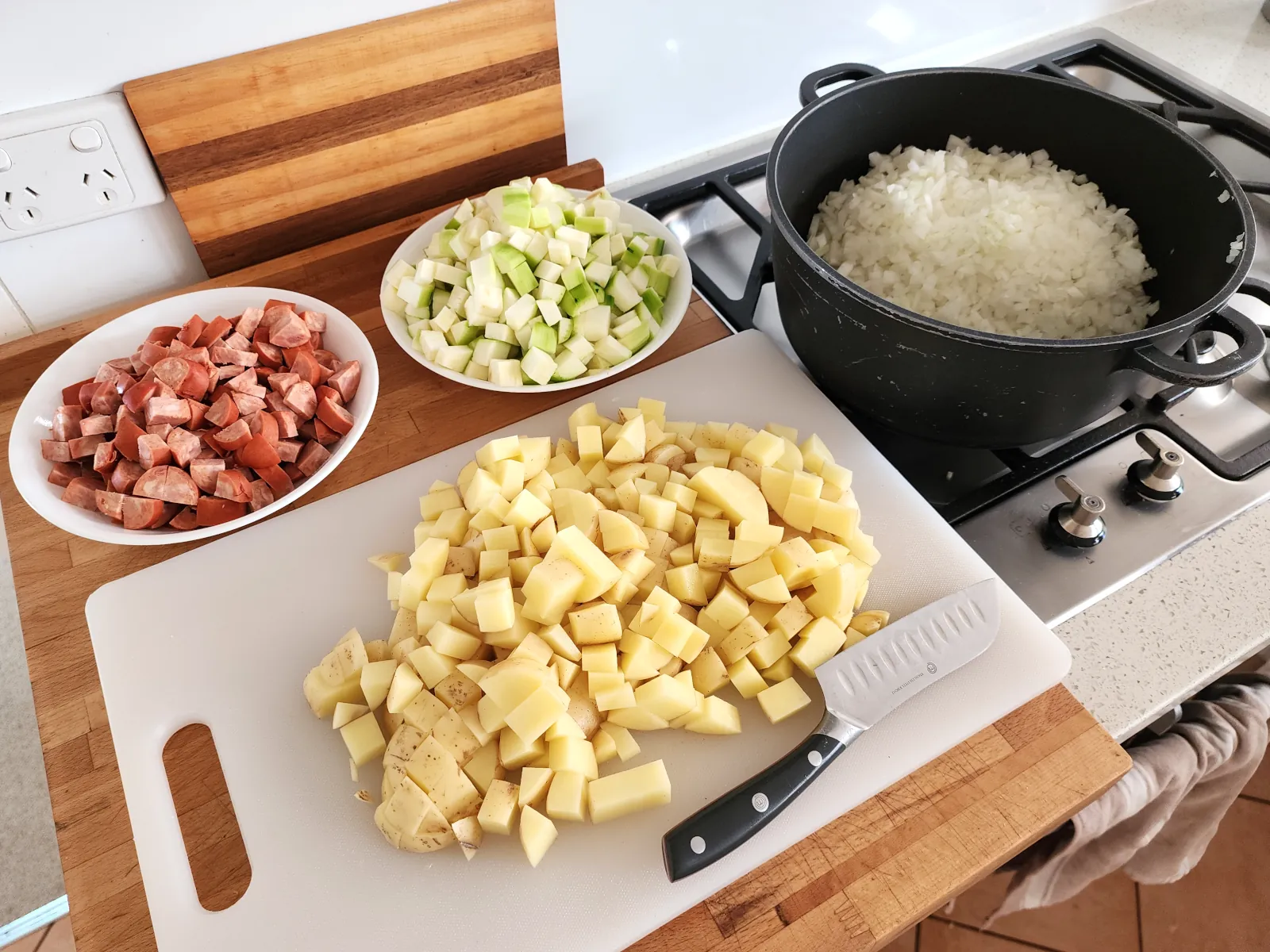 Diced vegetable ingredients - potato, zucchini and onion - and diced sausage ready to cook the potato goulash with sausage