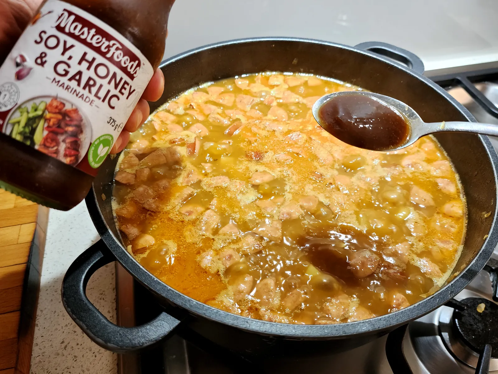 Flavoring the potato goulash with one table spoon of soy honey and garlic marinade