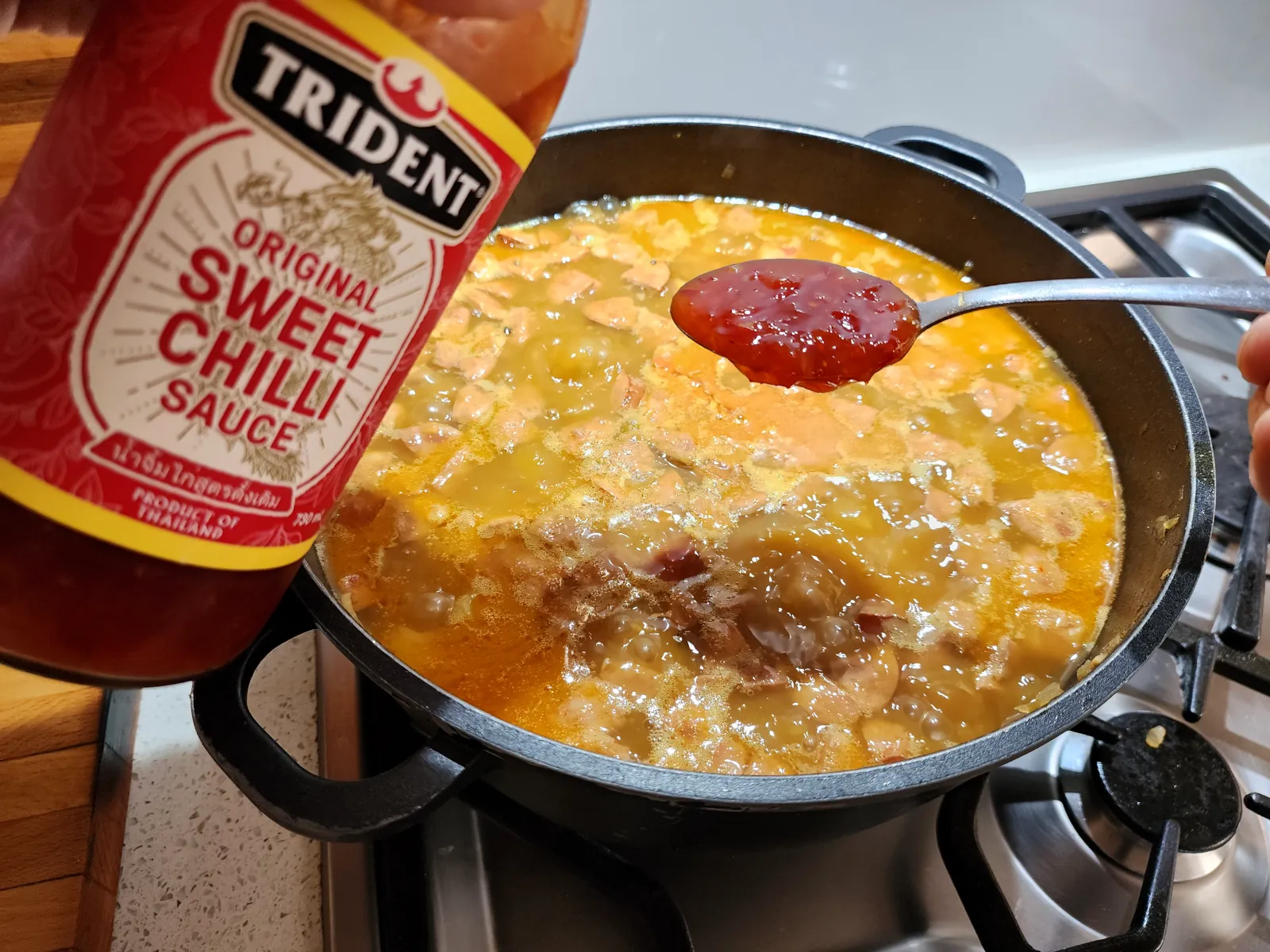 Flavoring the potato goulash with a one spoon of sweet chilli