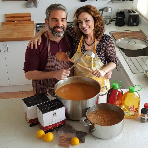 Markus and Bianca Kuchar from Earth, Food and Fire.com in the kitchen with two large pots of goulash.
