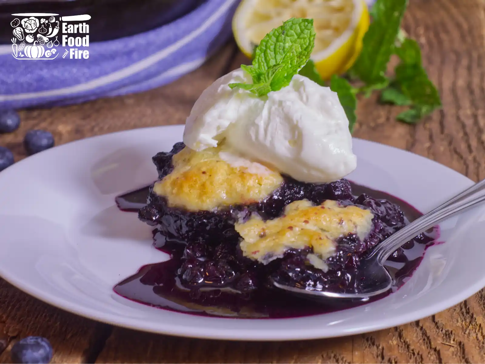 Blueberry cobbler served with ice cream and mint leaf decoration on a white plate