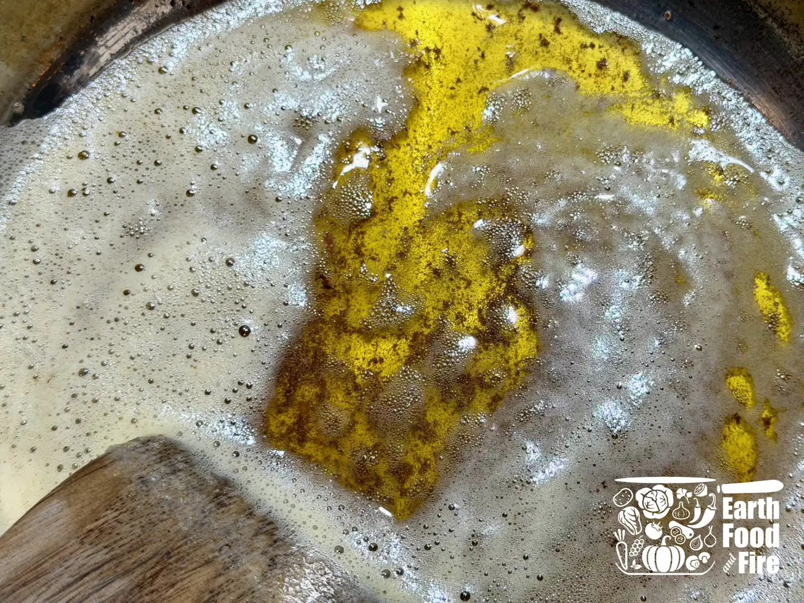 Melted butter being browned in a pan, with the small brown flecks of browned milk solids showing.