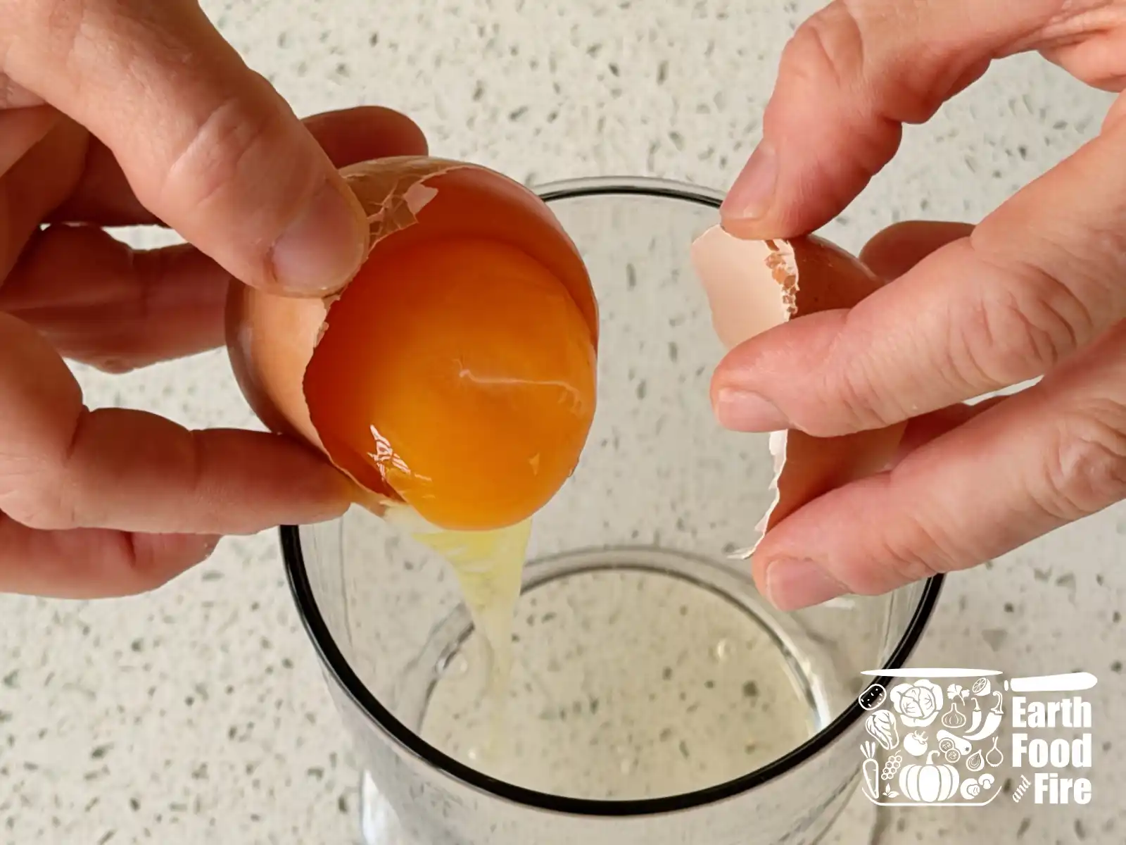 Cracking a fresh egg into a tall glass jar