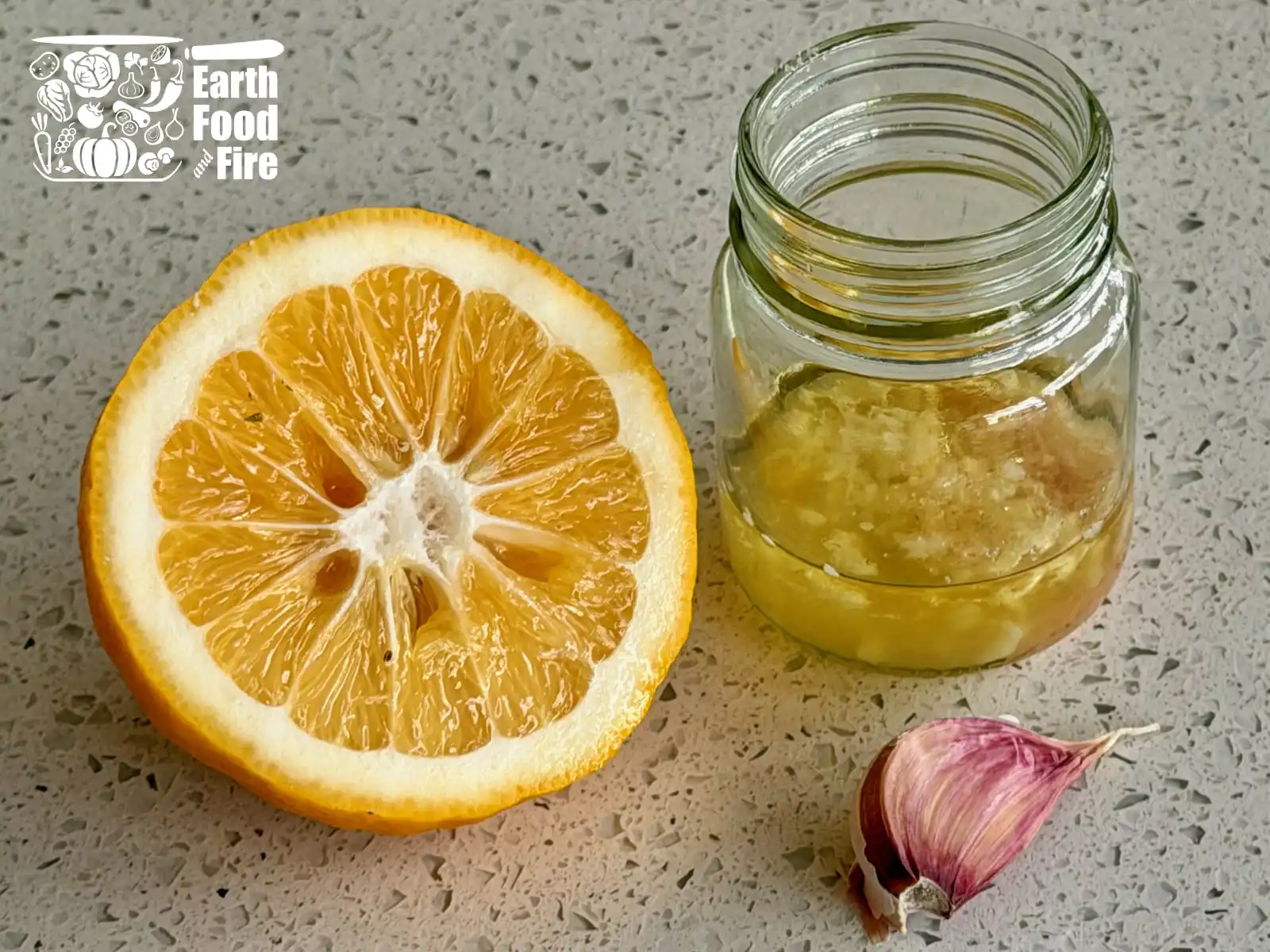 Garlic lemon dressing in a jar, with a clove of garlic and half lemon on a table