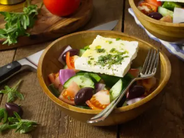 Traditional Greek Horiatiki salad served in a bowl on a wooden table
