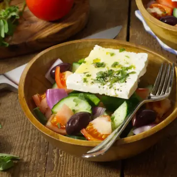 Traditional Greek Horiatiki salad served in a bowl on a wooden table