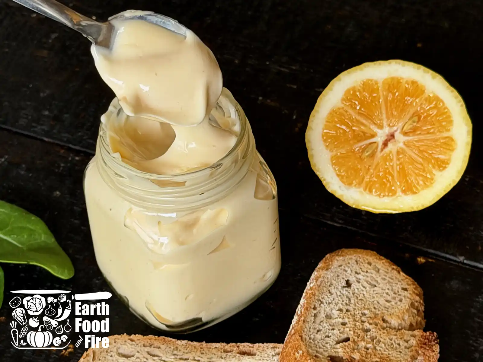 Homemade mayonnaise jar made according to the recipe on a table with toasted bread and half of a lemon