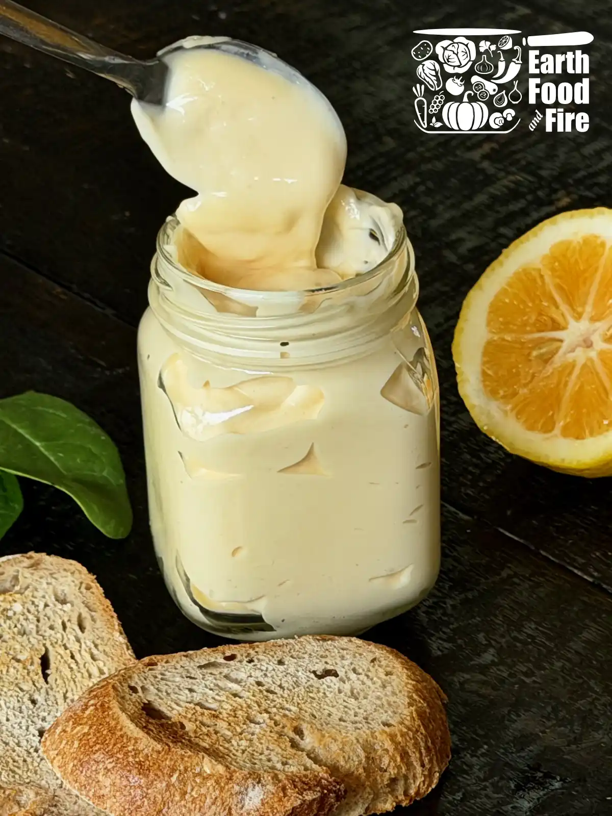 Creamy homemade mayonnaise recipe in a jar on a wooden table with a toasted bread and half of a lemon