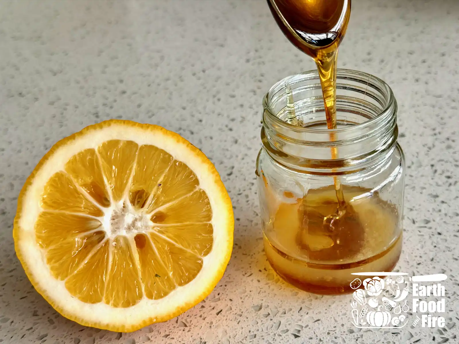 Honey lemon dressing in a jar, with half a lemon and spoon dripping the honey
