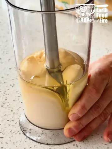 Stick blender being slowly lifted to mix the homemade mayonnaise