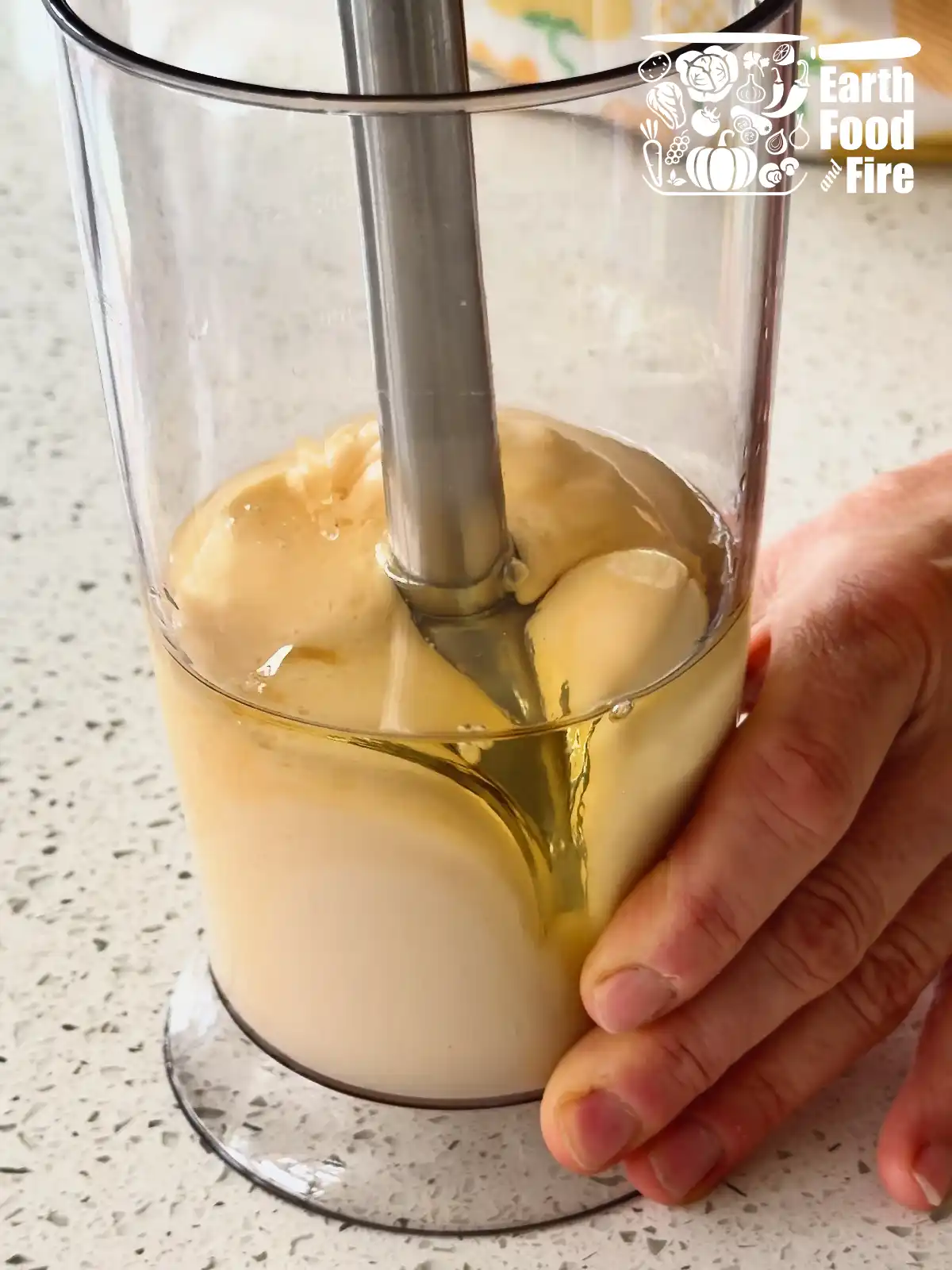 Stick blender being slowly lifted to mix the homemade mayonnaise