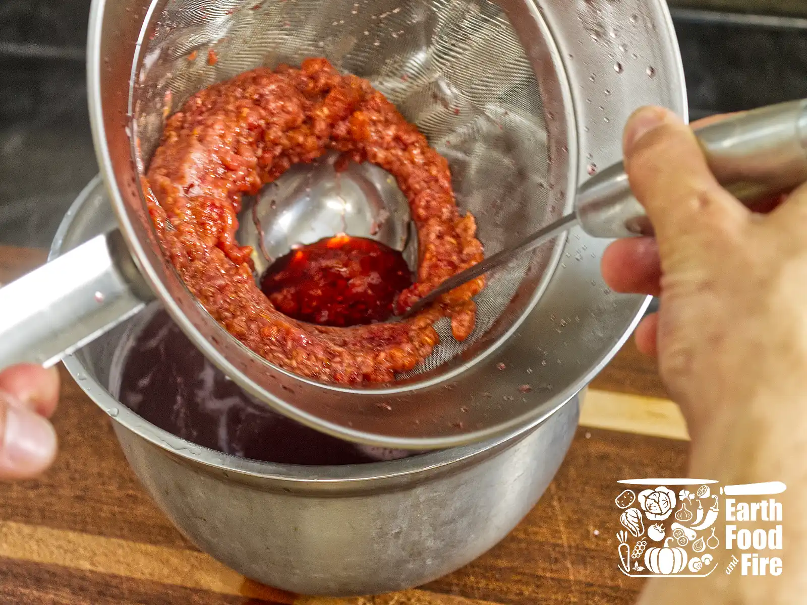 Mashing raspberry pulp to squeeze juice out