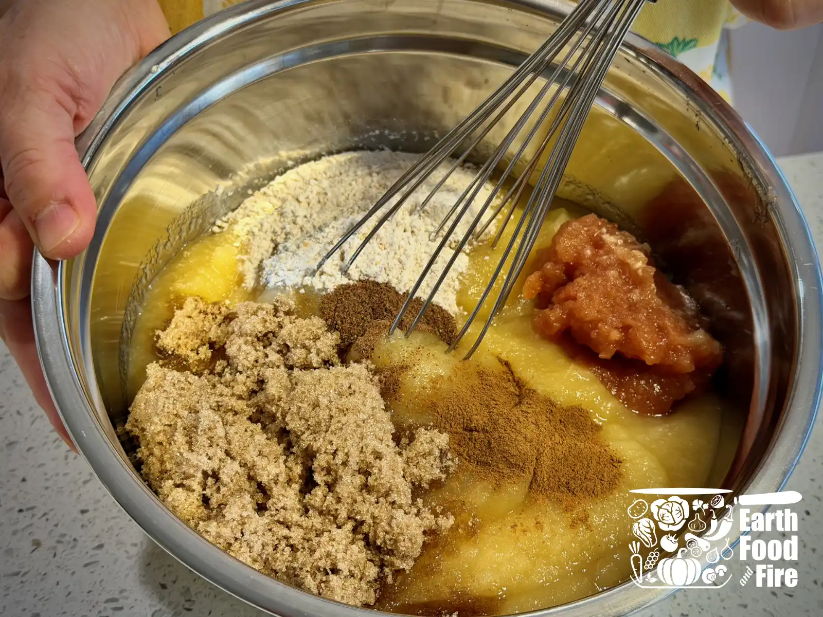 Mixing applesauce crisp filling ingredients in a bowl with a hand whisk