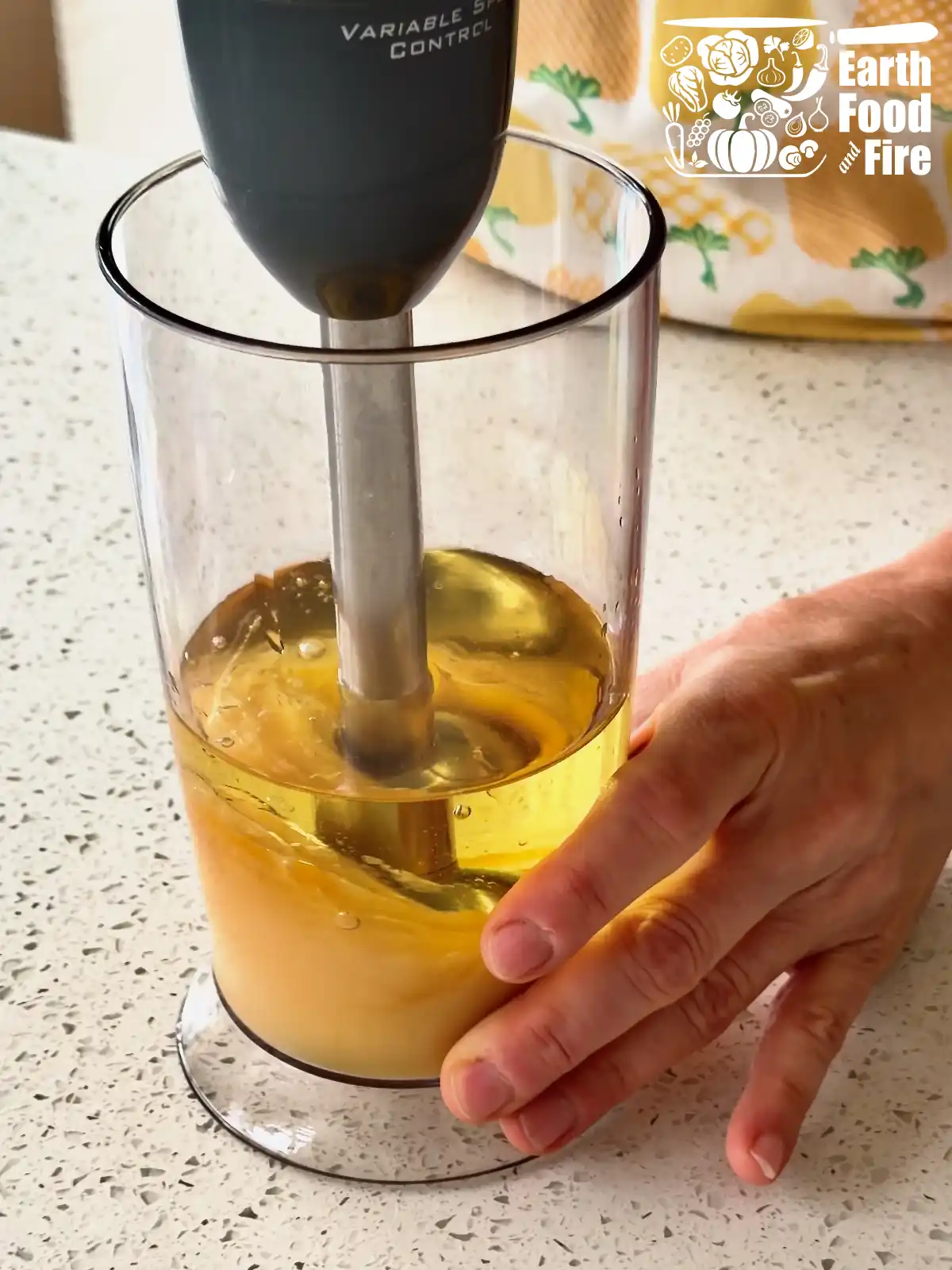 Stick blender sitting flat at the bottom of a jar while white mayonnaise is starting to rise through the oil