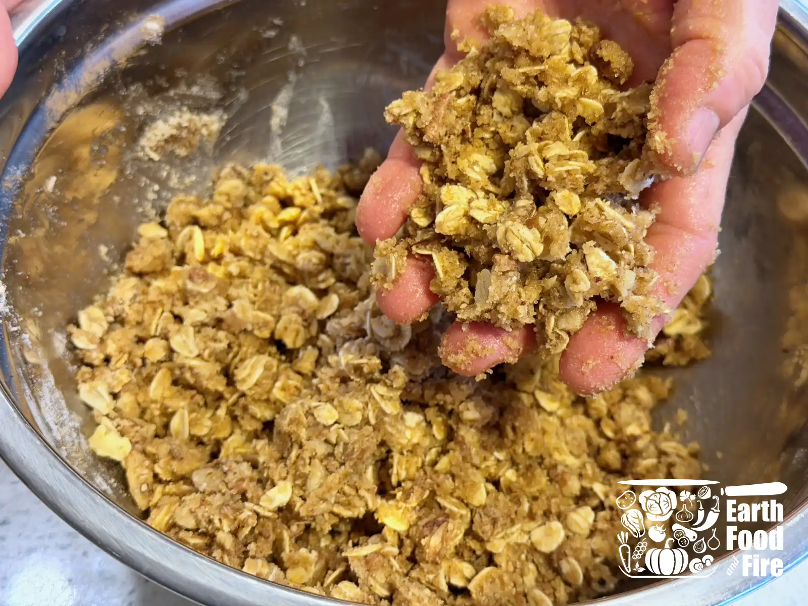 Hand holding the crumbed mixed applesauce crisp topping ingredients