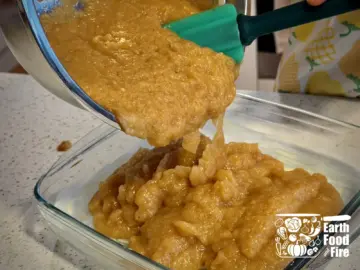 Mixed applesauce crisp filling being poured from the mixing bowl into the baking tray.