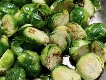 Halved Brussels sprouts searing cut-side down in a hot skillet with olive oil, showing golden-brown caramelized marks.