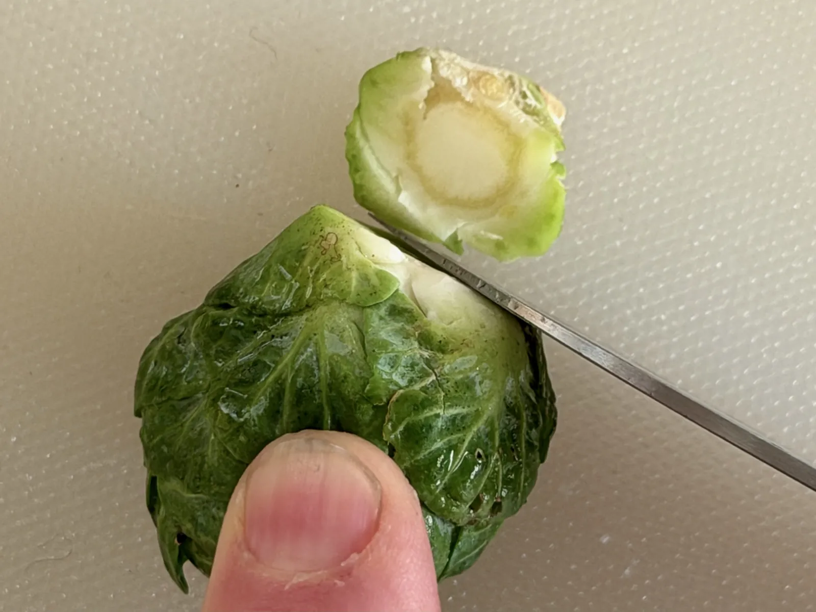 Trimming the bottom end of sprouts in half for sautéed Brussels sprouts recipe