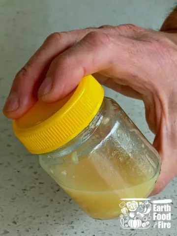 Jar with garlic lemon dressing being shaken in hand