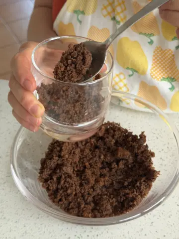 First layer: spooning the cake crumbles into glass