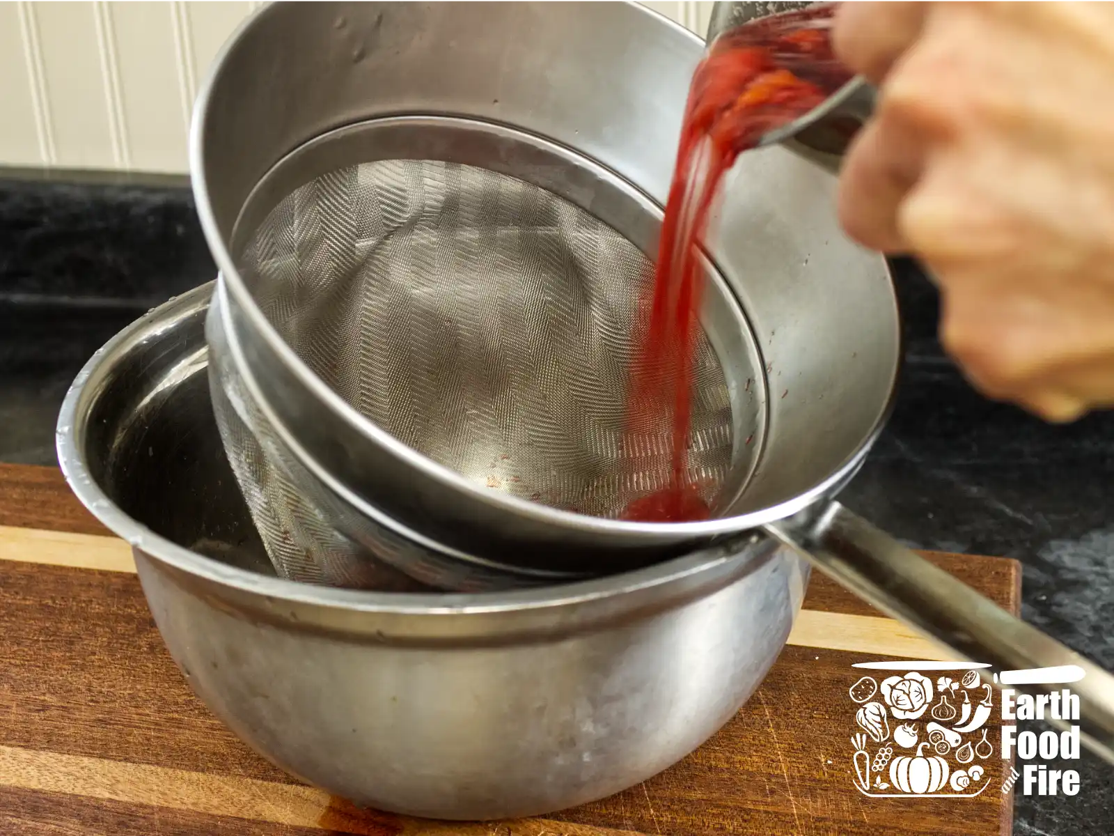 Straining raspberry cordial through a fine mesh